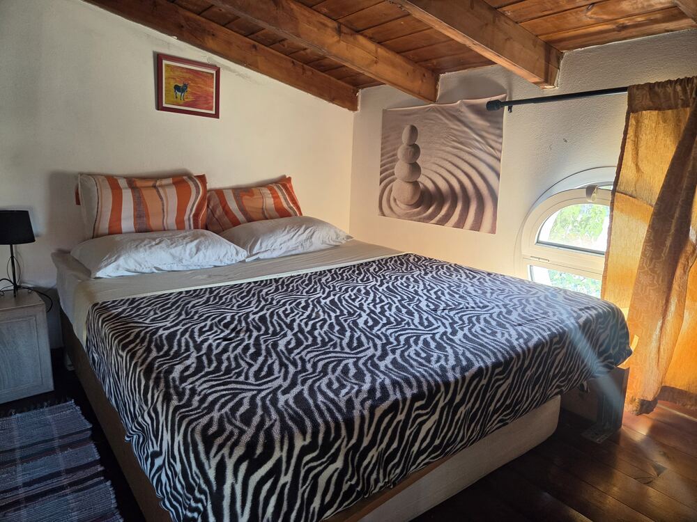 Room Onda — wood-beamed room with round window